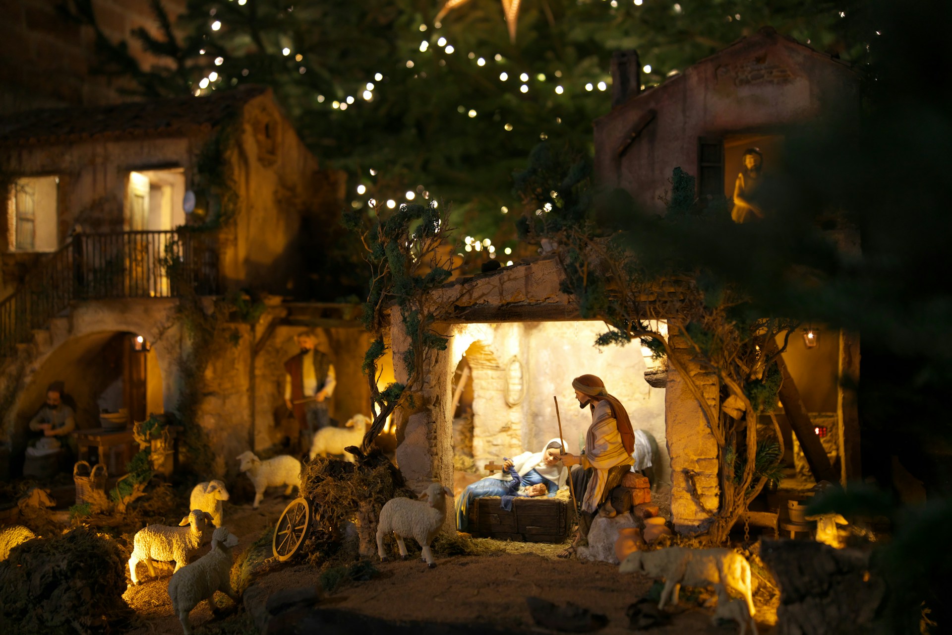Une crèche de Noël éclairée dans la pénombre : l'étable, les santons et les maisons de pierre du village